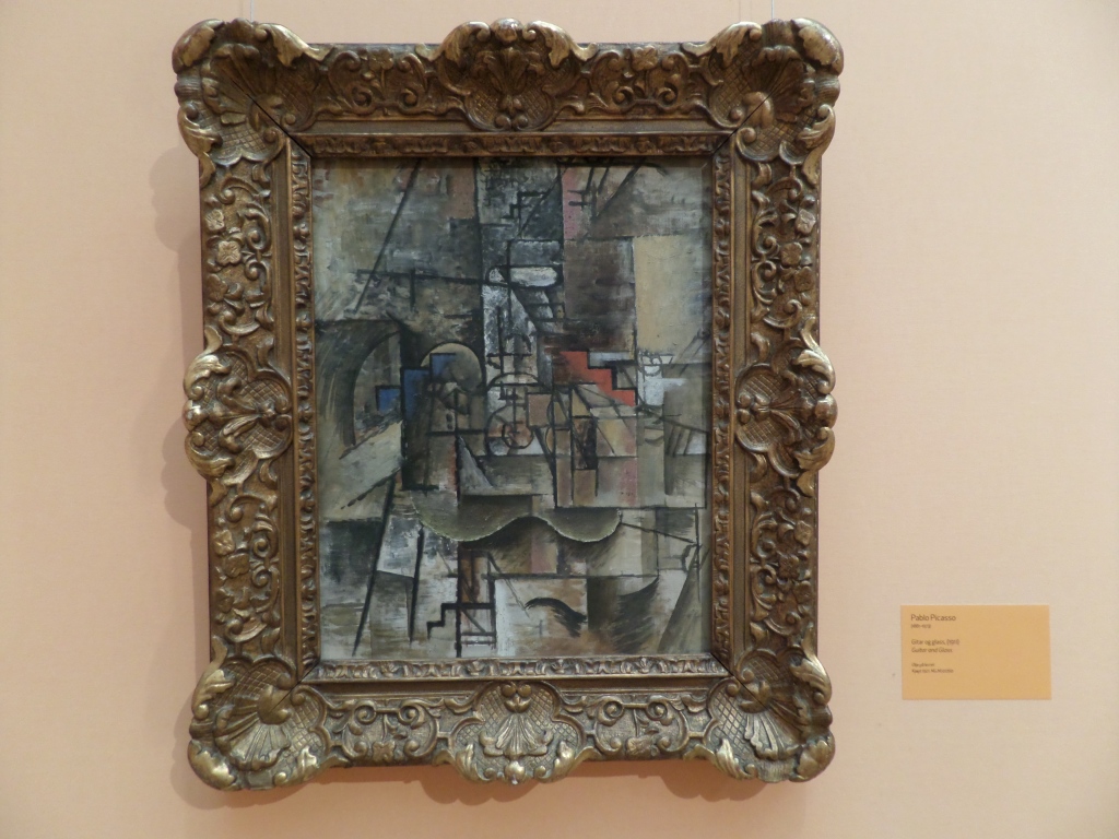 Kuvassa koristeellisissa kehyksissä oleva taulu, jossa abstrakti maalaus, mikä näyttää koostuvan erilaisista osioista.